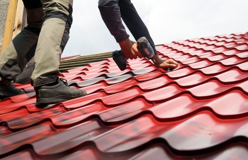 Roofers installing red metal tile roofing